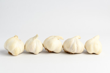 Fresh organic garlic on a white table, isolated on white background with soft focus, side view of tasty healthy vegan food
