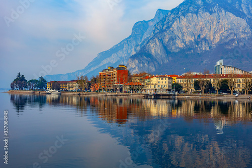 Lecco Italy February 16 The Picturesque Embankment Of Lake Como In Cloudy Weather And The Mountains Behind It Beautiful Reflection In The Water Buy This Stock Photo And Explore Similar