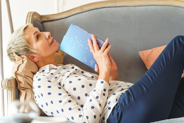 female holding an astrology book with both hands