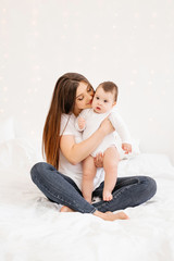 Wall Mural - Happy young mom hugs toddler in bed