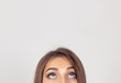 cropped image half face eyes of woman looking up white grey wall