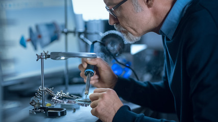 Wall Mural - Portrait of Focused Middle Aged Engineer in Glasses Working with High Precision Laser Equipment, Using Lenses and Testing Optics for Accuracy Required Electronics