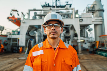 filipino deck officer on deck of vessel or ship , wearing ppe personal protective equipment - helmet