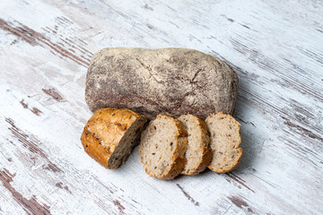 Top view of two fresh healthy loaves of multi-grain seedy and rye bread on rustic wooden table. Assorted homemade bread, whole and sliced. Close-up. Background, copy space