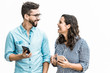 © Mangostar - Happy excited couple with smartphones discussing awesome news. Young woman in casual and man in glasses in glasses posing isolated over white background. Mobile app or good news concept