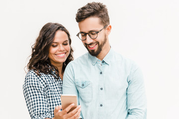 Happy cheerful woman showing message on phone to her boyfriend. Young woman in casual and man in glasses in glasses posing isolated over white background. Good news concept