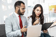 © Mangostar - Coworkers with folder and laptop discussing work. Professional multiethnic businessman and businesswoman working with laptop computer and documents in office. Cooperation concept
