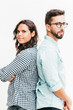© Mangostar - Serious pensive couple standing back-to-back, looking at camera. Young woman in casual and man in glasses in glasses posing isolated over white background. Relationship and support concept