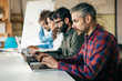 © Mangostar - Startup team sitting at meeting table, using laptops. Business colleagues in casual working together in contemporary office space. Collaboration concept