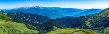 Panoramic View Over The Green Valley, Surrounded By High Mountains With Snow On A Clear Summer Day.