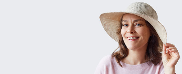 Portrait of a happy woman in a hat on a light background,  banner with copy space