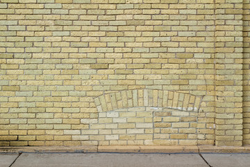  Shabby chic old yellow brick wall texture background with natural weathered appearance, showing a bricked-in arched basement window