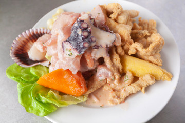 Wall Mural - Peruvian food: fish ceviche and chicharron de pescado with fried cassava, sweet corn and sweet potato, served on a white plate