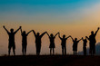 © EKKAPON - The shadow of a happy family holding hands in the meadow during sunset Happy family enjoying life together outdoors Round dance celebration ceremony