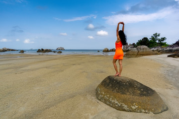 Wall Mural - Standing woman on big stone in orange dress