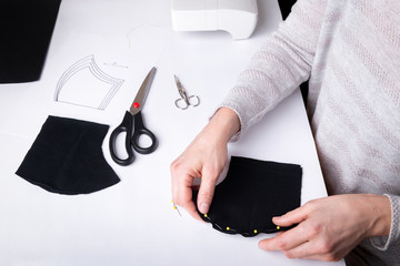 Wall Mural - Woman hands sewing a face mask from the black cloth.