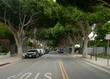 Long shot of a suburb road lined with trees parked cars