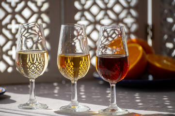 Glasses with cold dry fino and sweet cream sherry fortified wine in sunlights, andalusian style interior on background