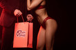 cropped view of sensual couple with shopping bag from sex shop on black with red light