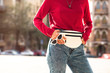 © ClaudiK - Street style fashion details. street style fashion detail, close-up of a woman wearing a red rose sweater, vintage sunglasses, banana bag and blue jeans. Horizontal.