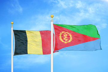 Belgium and Eritrea two flags on flagpoles and blue cloudy sky