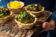 Vegan tarts with long rice filling and stuffed with laminaria kelp seaweed salad in woman hands. Healthy snack.