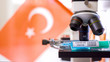 The Turkey flag on the back of the microscope with the syringe for coronavirus vaccine COVID-19