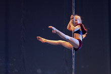 Young Girl Athlete Gymnast Shows An Acrobatic Performance On A Pylon.