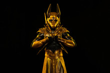 A Male Actor In A Suit Of An Egyptian Mythology Character, The Golden Deity Jackal Anubis, Twists Buugeng In Yellow Light On A Black Background