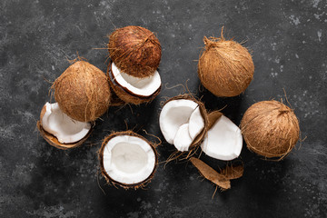 Wall Mural - Coconuts cracked and whole on black background, top view