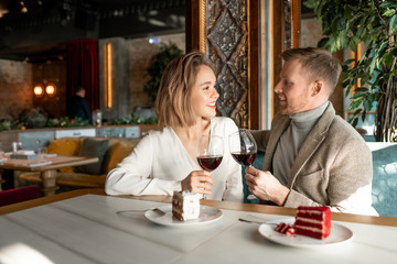 Wall Mural - Young romantic couple with glasses of red wine talking and making toast