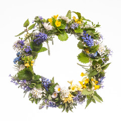 Wreath of wild spring flowers on white background