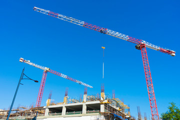 Single high-rise construction crane on the blue sky background. Building construction site with crane. 