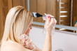 © Angelov - A middle-aged woman dyes her hair at home, indoors