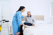 © Creativa Images - Senior man sitting on the bed helped by nurse