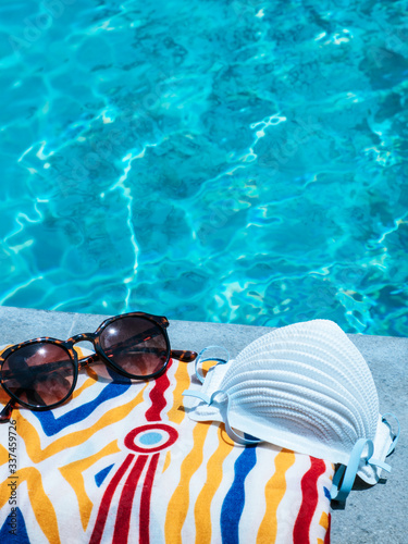 Fotografía Face mask, a towel and a pair of sunglasses laying beside a swimming pool