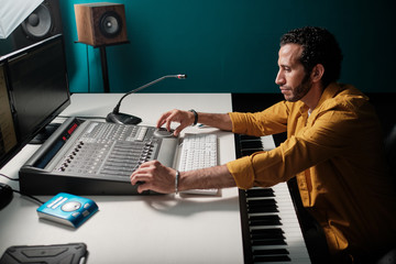 Wall Mural - Man working on music controllers at home studio