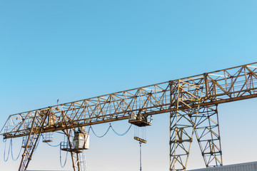 Vintage working gantry crane rusty yellow, bottom view, close-up against a blue spring sky