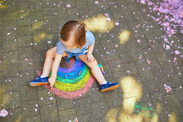 Wall Mural - toddler girl drawing rainbow with colorful chalks