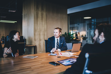 Wall Mural - Successful male and female partners have briefing collaboration on business project using modern laptop devices for analyzing information during brainstorming in conference room, group of experts