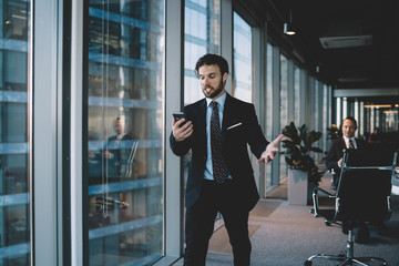 Wall Mural - Furious male entrepreneur in suit disappointed with bad nes and mails using mobile phone for sending message,expressive caucasian businessman screaming on smartphone having problem with using device