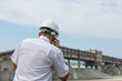 © Model Republic - Mining engineer in white shirt and helmet holding phone supervises the work of the granite processing workshop