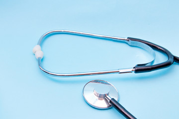 Black Stethoscope isolated on blue background, top view. Medical tool