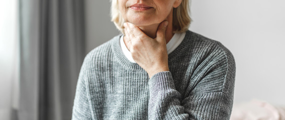 Sick senior adult elderly women touching the neck feeling unwell coughing with sore throat pain.Healthcare and medicine concept