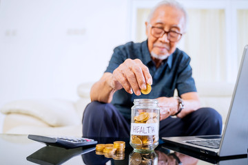 Old man savings coins in a jar with health text