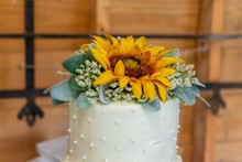Closeup Shot Of A White Cake With A Sunflower On Top On A Wooden Background