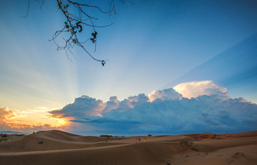 Cham women in traditional dress walking across sand dunes to collecting water at Nam Cuong sand hill, Phan Rang, Vietnam. Many Cham people retain, Ninh Thuan province