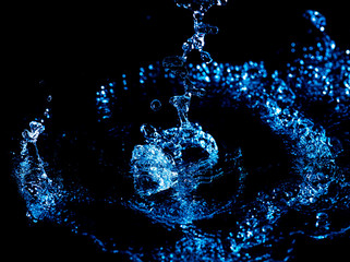 Wall Mural - Splashes and drops of blue water on a black .