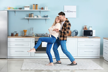 Wall Mural - Happy dancing young couple in kitchen