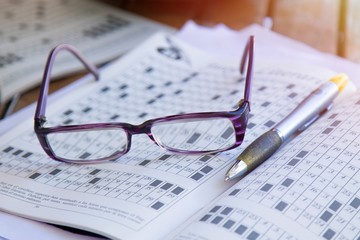 crossword or hobby books, glasses and pen, games and hobbies concept